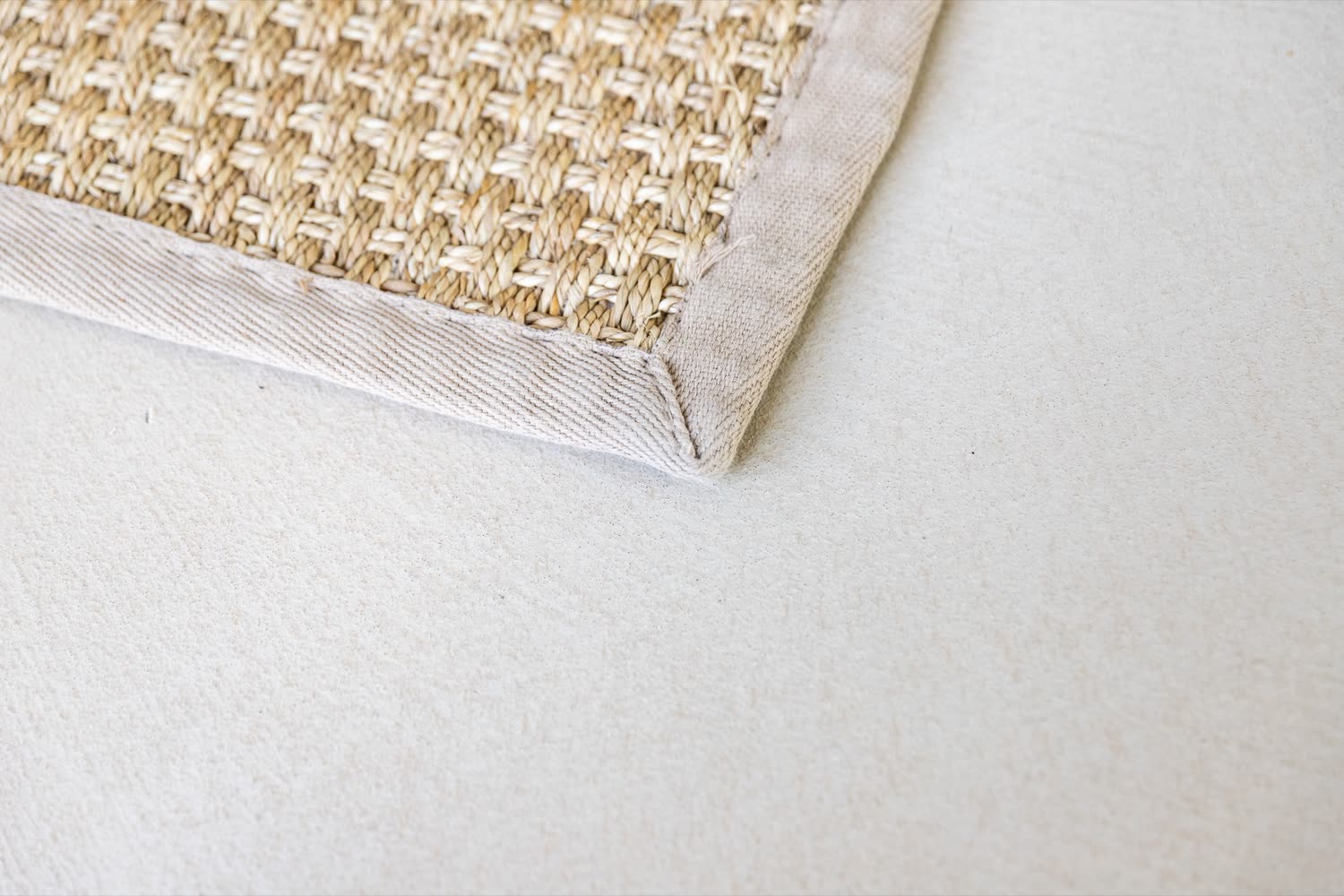 Detail van een naadloze gietvloer, met de rand van een vloerkleed erop