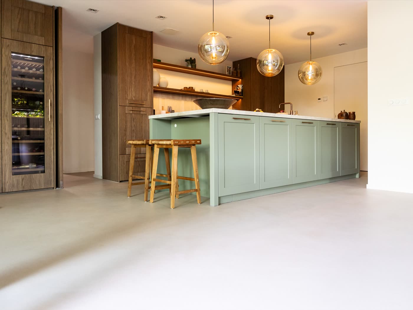 Opgeleverde leefkeuken met eiland, houten kastenwand en naadloze gietvloer